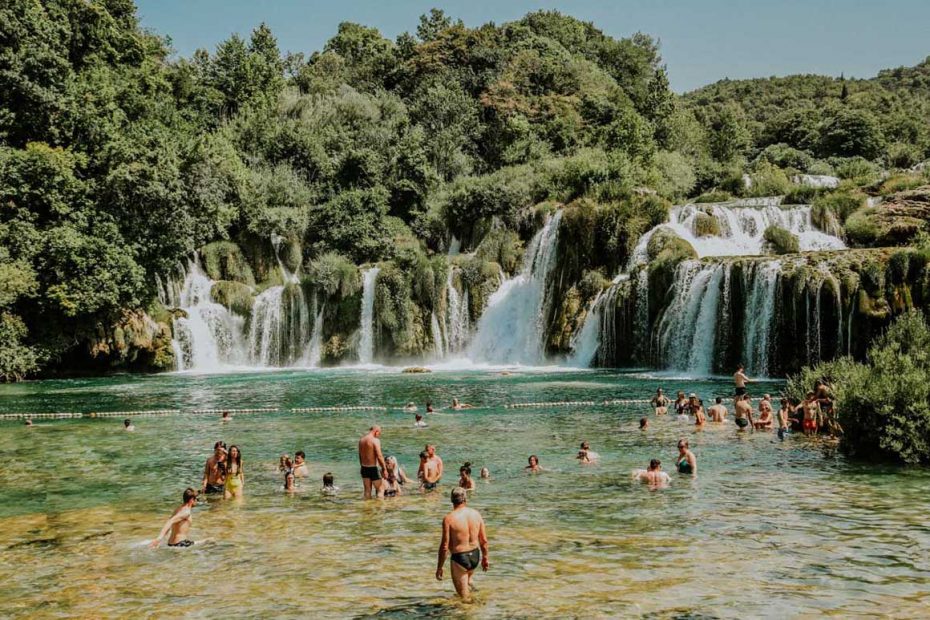 people enjoying swimming by Krka waterfalls